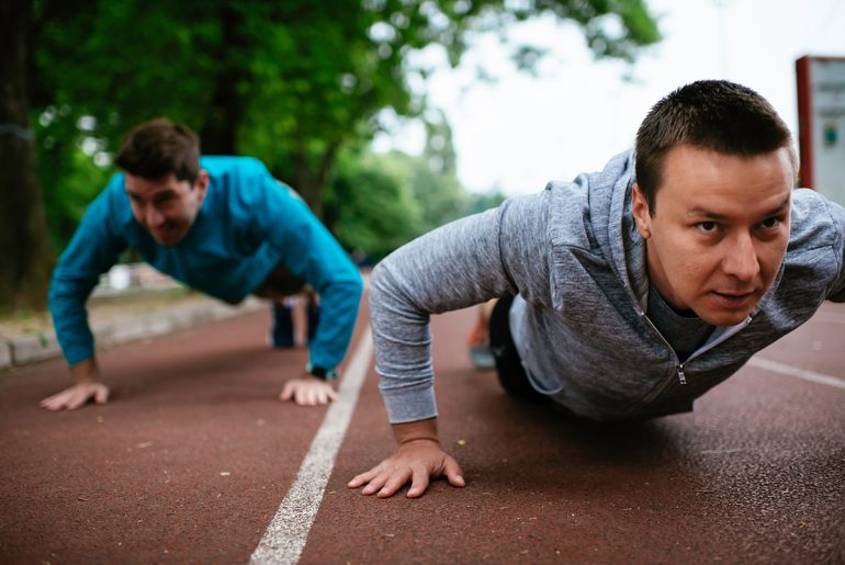 Zwei Männer machen Liegestütze auf dem Sportplatz