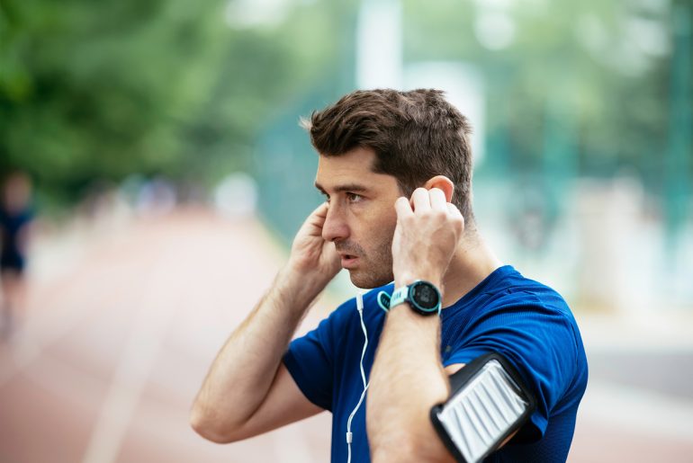 Junger Mann auf dem Sportplatz mit Headphones sieht seinen Gegenüber an