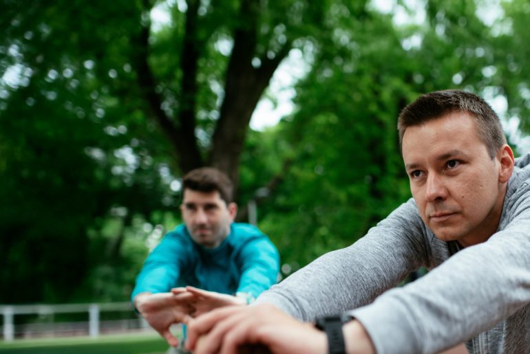 Zwei Freunde beim Stretching auf dem Sportplatz