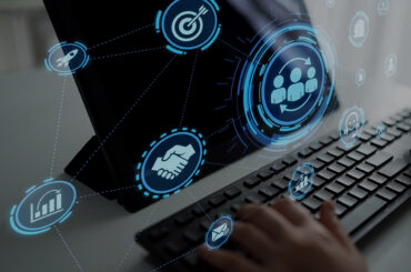 Hände an Tastatur sowie ein Monitor mit virtuellen Symbolen
